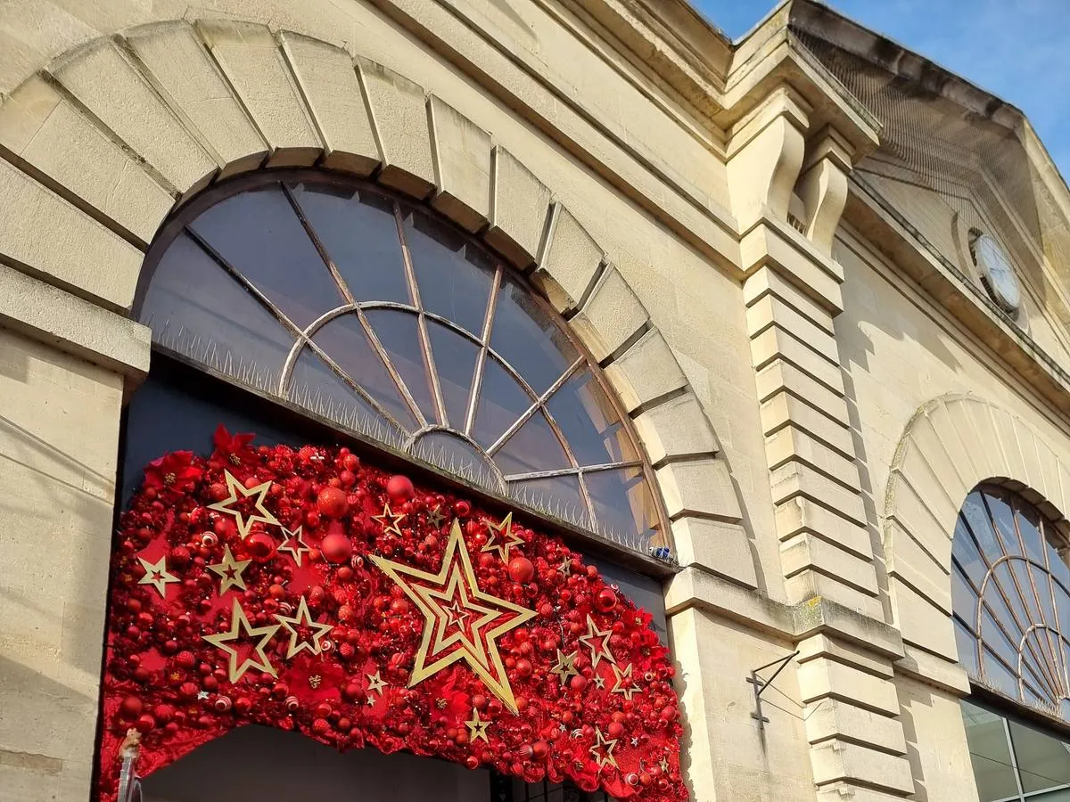 Red and gold Christmas stars decorating the arched stone entrance to Market Walk, Salisbury